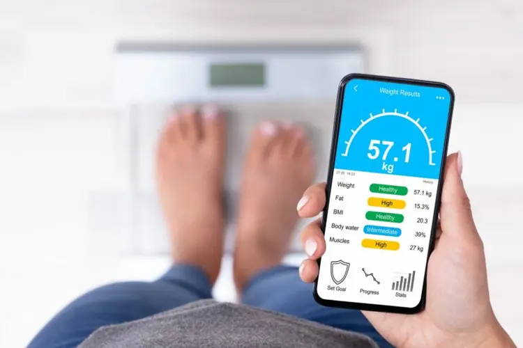 IMC et poids - comprendre et agir pour sa santé - Femme devant une balance intelligente avec une application mobile affichant l’évolution de l’IMC