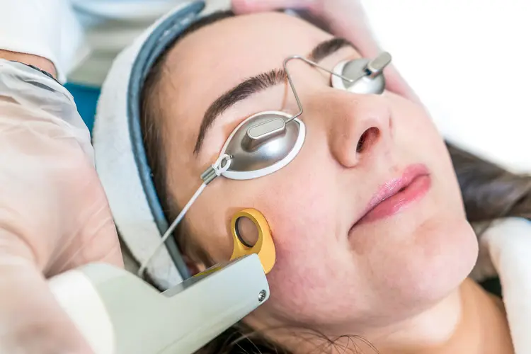 Rosacée : causes, soins et laser vasculaire visage - Un médecin esthétique en train de pratiquer un traitement laser sur une joue